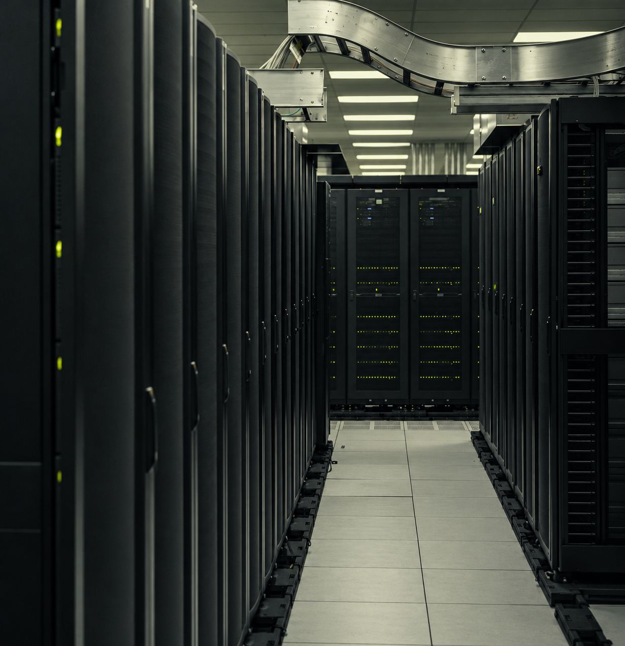 An orderly aisle of closed server racks with graphite tones and subtle lime status lights